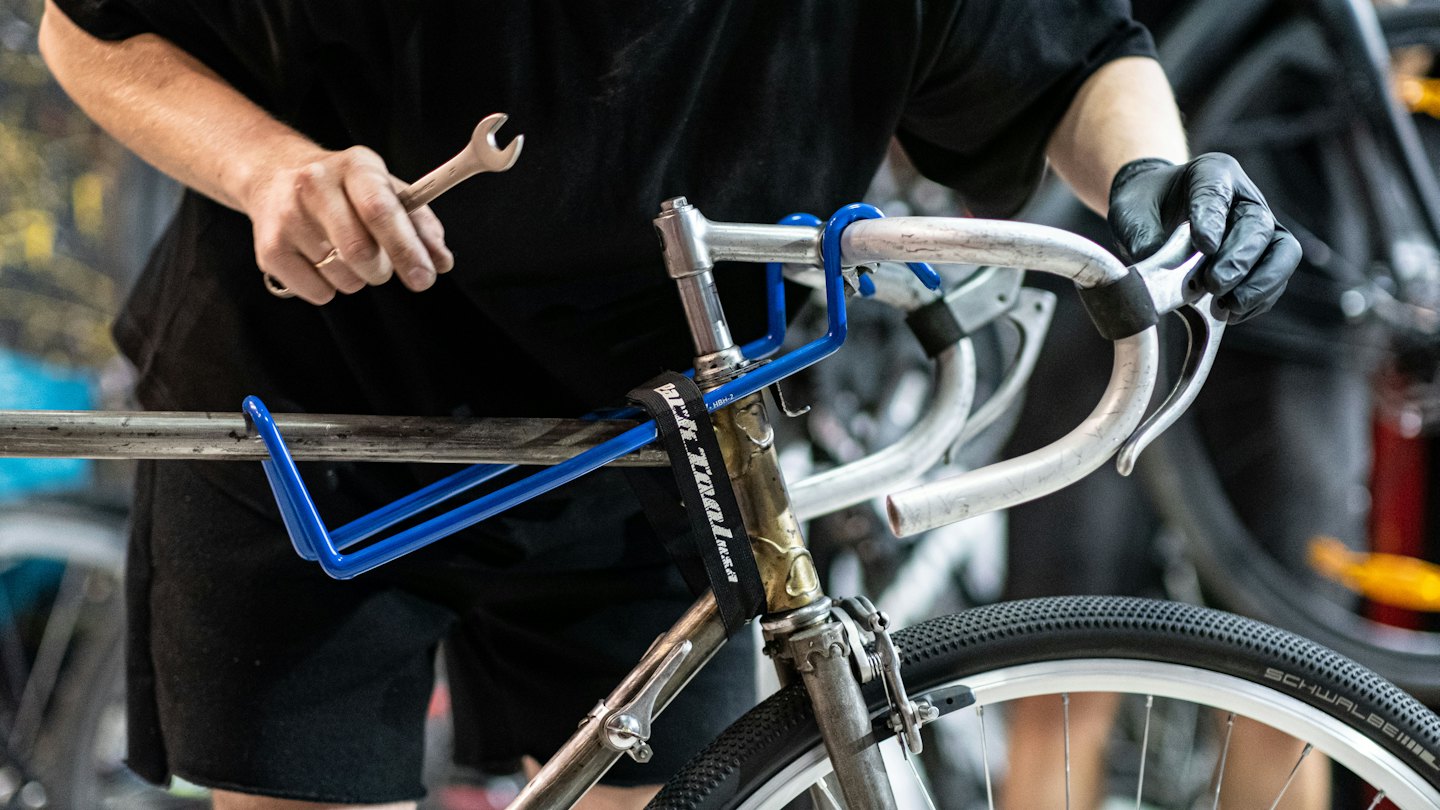 Meccanico di biciclette lavora sul manubrio di una bicicletta con una chiave inglese.