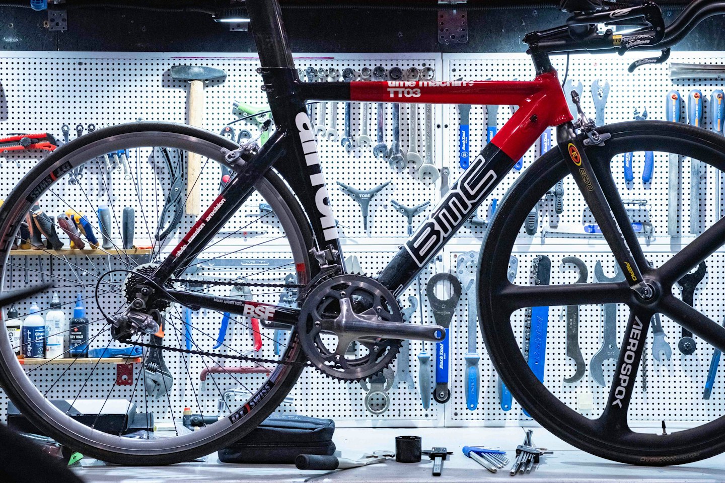 Meccanico che ripara una bicicletta da corsa rossa e nera in un'officina.