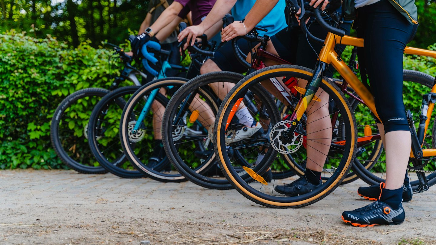 Ciclisti in abbigliamento sportivo su bici gravel su un sentiero sterrato.